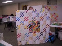Barbara-M.-shows-her-scrap-quilt-scaled